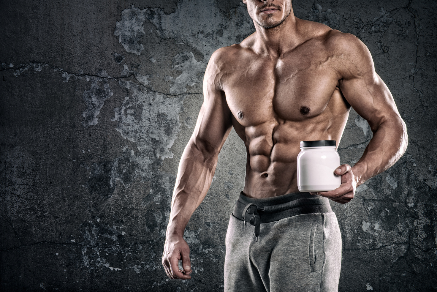 Bodybuilder holding bottle of supplements